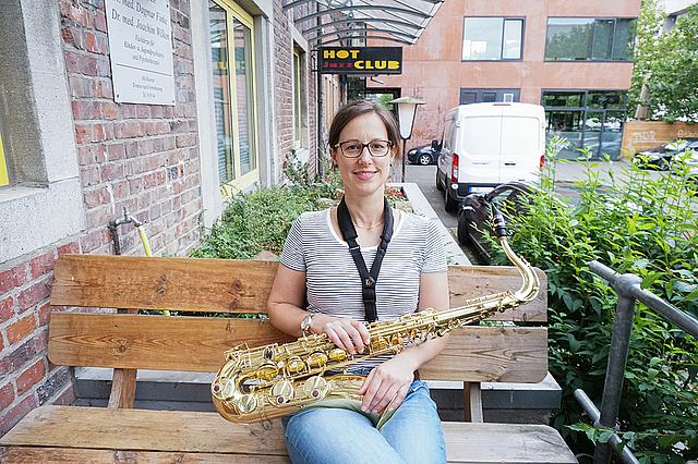 Frau mit Saxophon sitzt auf einer Bank