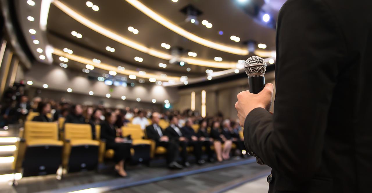 Person mit Mikrofon vor Publikum im Hörsaal