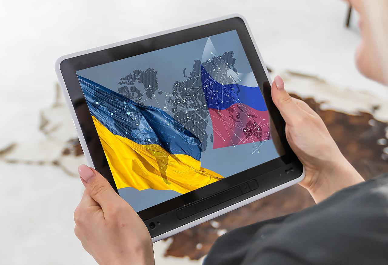 Person hält Tablet mit Ukraine- und Russland-Flaggen