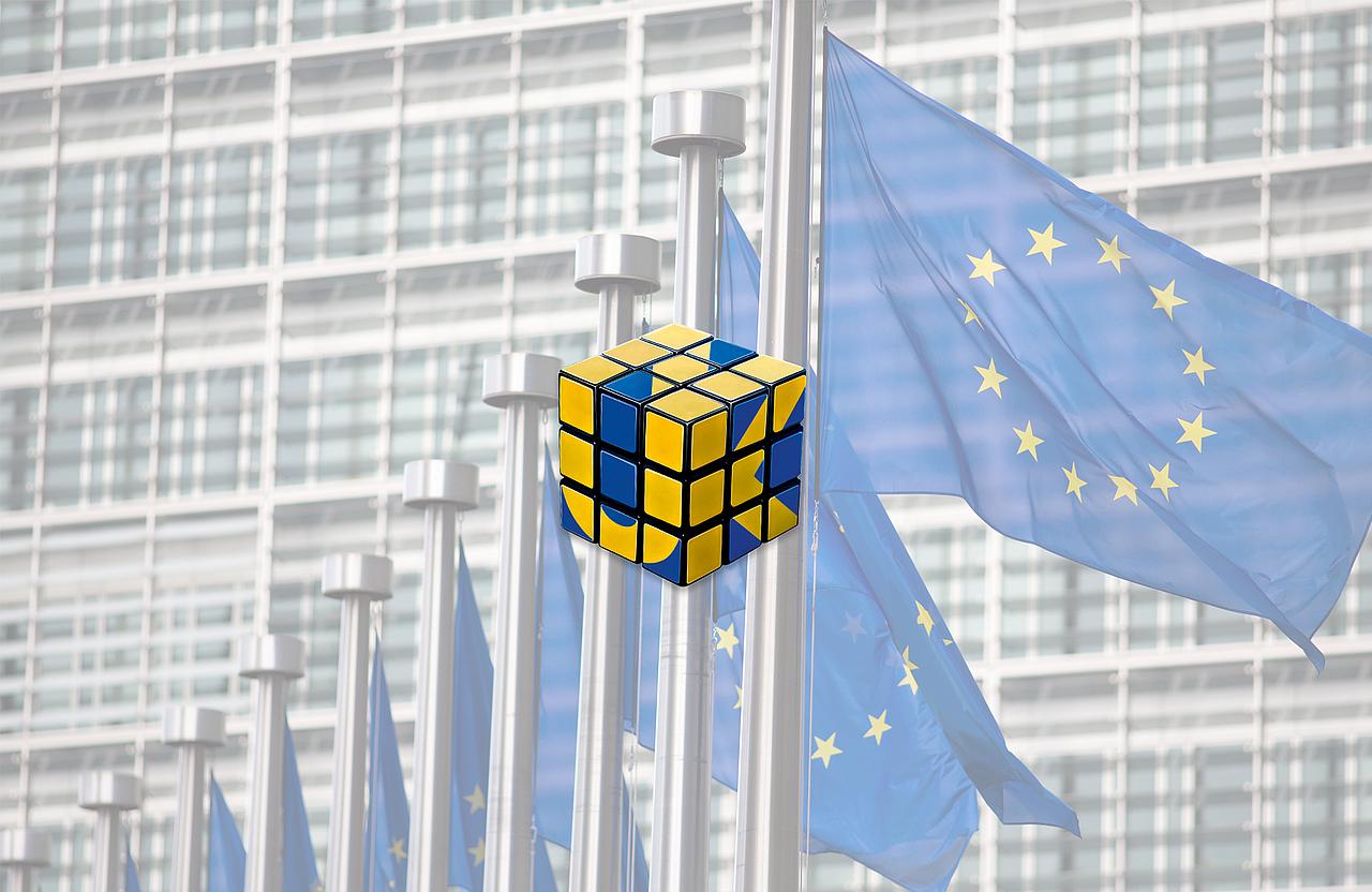 Blau-gelber Zauberwürfel, EU-Flaggen im Hintergrund