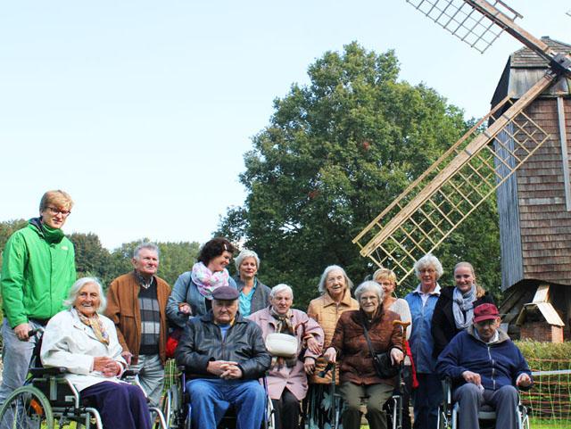 Gruppenfoto mit Rollstühlen vor historischer Mühle